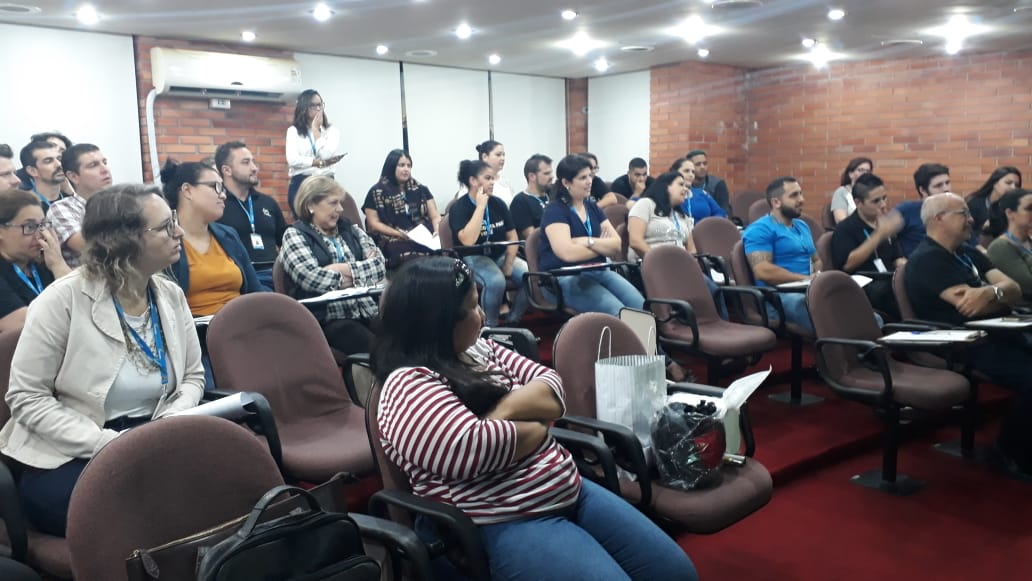 Turma composta por diversas pessoas sentadas observando a aula