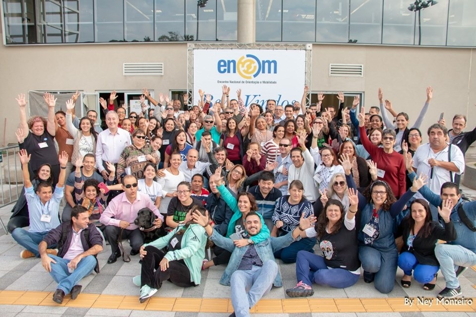Grande grupo de pessoas posa para foto em área externa do evento