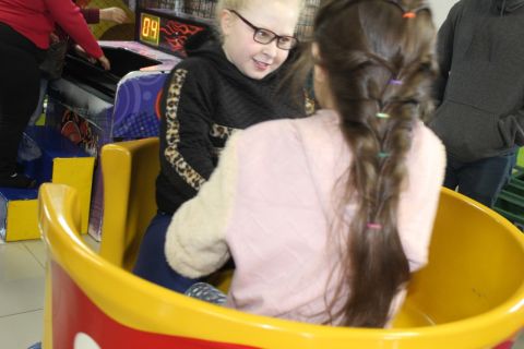 Duas associadas da ADEVIC aparecem brincando de frente uma para a outra, dentro de um brinquedo amarelo