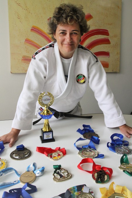 Atleta Giovana Pilla, atendida pela ADEVIC, posa para foto diante das várias medalhas que conquistou